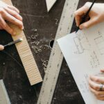 a person in plaid long sleeves drawing furniture on a bond paper